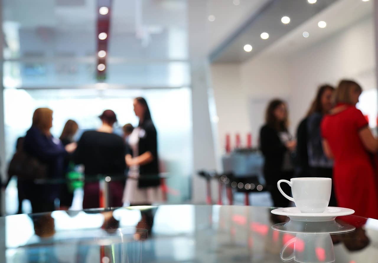 Un espace détente avec une tasse de café au premier plan et des silhouettes floues à l'arrière plan